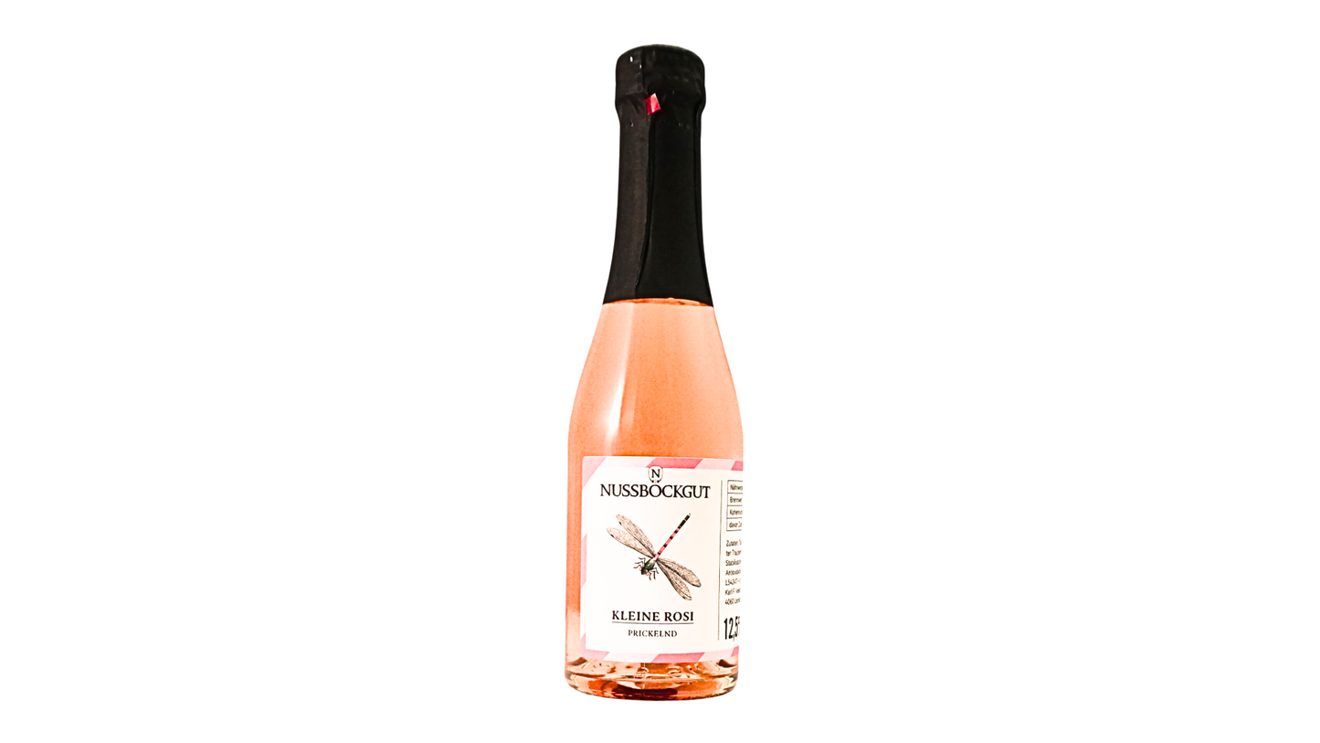 Auf dem Bild ist eine 0,20 l Schaumweinflasche - ein Direktträger als Roseschaumwein - dargestellt. Am Etikett befindet sich der Name des Weingutes - Nussböckgut - der Umriss von OÖ sowie unser Markenzeichen für die Rosemarie, die Libelle, als Nützling des Weingartens.